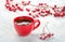 Red cup with coffee and branches with hawthorn berries on old white wooden table. Selective focus