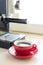 Red cup of coffee with coffee machine behind