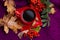 Red cup with coffee on saucer on purple knitted background with autumn leaves and rowan berries