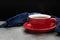 Red cup of coffee with smoke and blue fabric on cement background