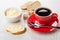 Red cup with coffee, spoon, sandwich with melted cheese, sugar