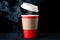 Red cup of coffee with a white cap on a black background. Hot drink with steam