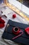 Red cup of espresso coffee with caramel cane on dark wooden tray with Christmas decoration and garland lights.