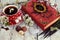 Red cup of flower tea with black candles, candies and witch book on table