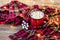 Red cup with hot coffee and sweet marshmallows on wooden table with plaid in Christmas decorations with garland lights