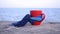 Red cup with hot coffee tea, tied with blue knitted scarf stands on stone