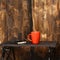 Red cup and notebook with pen on black table.