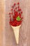 Red currant fruits in an ice cream cone on wood