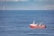 A red cutter on the North sea with a cargo ship and a wind turbine in the background