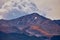 Red and dark gray mountain with large approaching clouds