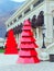Red decorative glossy Christmas trees stand in front of the building porch. Corner view