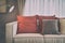 Red and deep brown linen pillows on beige linen sofa with a brass lamp