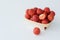 Red delicious strawberry in light square wooden plate on white background.