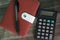 red diary book with black inks ball pen for writing and calculate on the wooden table