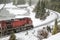 Red Diesel Locomotive on Tracks Running By a River During a Blizzard