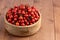 red dog-rose rosehip fruits in a wooden bowl on wooden table