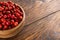 red dog-rose rosehip fruits in a wooden bowl on wooden table