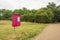 Red dog waste bin beside footpath in a park