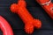 Red dogs toys, bone, a collar on black wooden background. Accessories for a puppy, care concept. Top view, close up.