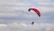 Red dome of a motor paraglider against a blue evening summer sky