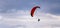 Red dome of a motor paraglider against a blue evening summer sky.