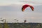 Red dome of a motor paraglider on blue sky.