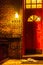 Red door on brick wall, side of a house at night with hanging lamp and newspaper