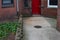 Red door rear entry to old brick apartment building with concrete walkway