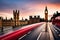 Red Double Decker buses drive down the Westminster Bridge in a morning traffic picture.