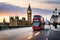 Red Double Decker buses drive down the Westminster Bridge in a morning traffic picture.