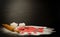 Red dough, cut out hearts, flour, eggs and rolling pin on a black background