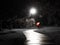 Red dressed pedestrian with red umbrella at a creepy dark bike path lit by street light