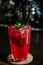 A red drink in a glass with ice cubes, strawberries,straw and mint leaves