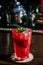 A red drink in a glass with ice cubes, strawberries,straw and mint leaves