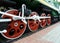 Red driving wheels of a steam locomotive, connected by levers