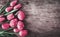 Red easter eggs and pink tulip flower on vintage wooden table from above