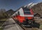 Red electric fast train in Austria Alps mountains