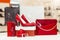 Red elegant leather women shoes with high heels, women purse, wallet and shopping bags in the background at the store