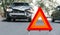 Red emergency stop triangle sign on road in car accident scene. Broken SUV car on road at traffic accident. Car crash traffic