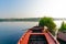 Red empty boat moored near some bushes on a blue serene river