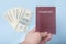 Red empty passport in the man`s hand. Dollars. Blue background