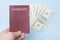 Red empty passport in the man`s hand. Dollars. Blue background
