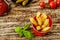 Red enameled cup with potato fries served with tomato sauce and pickled cucumbers in ceramic pots, decorated with basil leaves