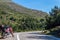 A red enduro motorcycle stands in side of the asphalt road, green nature