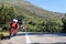 A red enduro motorcycle stands in side of the asphalt road, green nature