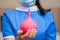 Red enema is close up. Medical concept of hygiene procedures. Enema in the hands of a nurse in blue uniform