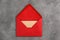 Red envelope with card on grey background, top view. Mail service