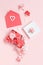 Red envelope, hearts and gift box full of flowers over a light pink background