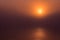 Red epic sunset over lake with reflection. Calm water and scenic sky merge together in mist.