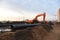 Red excavator during groundwork on construction site. Hydraulic backhoe on earthworks.